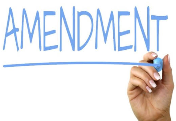 A hand writing the word "Amendment" in blue marker and underlining it